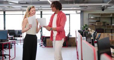 Çeşitli iş arkadaşları kırmızı çerçeveli masalar ve pirinç masa lambasıyla açık planlı ofiste kutlama yapıyorlar. Meslektaşlar, tezahürat, takım çalışması, başarı, coşku, verimlilik, çalışma alanı