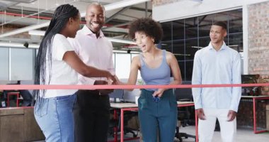 Çeşitli meslektaşlar modern ofiste makas ve neşeli ruhla kırmızı kurdele kesiyor. Kutlama, takım çalışması, başarı, yenilik, modern, profesyonel, ofis