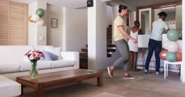 Partide, Arkadaşlar evde kutlama için hazırlanıyor, neşe dolu balonlar ve kadehler taşıyor. Parti, dostluk, şenlik, ev toplantısı, kadeh kaldırma, kahkaha