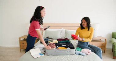 Çok ırklı genç yetişkin ve genç kız kardeşler pembe spor ayakkabılarıyla bavullarını yatak odasına topluyor. Modern, minimalist, İskandinav, hazırlık, organizasyon, katlama, bagaj