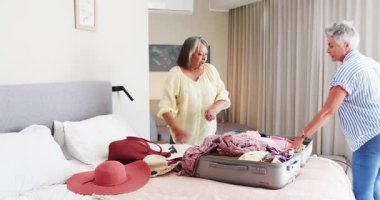 Modern eve seyahat için toplanan kıdemli arkadaşlar şapka ve kıyafetlerle bavul kullanıyorlar. Toplanma, arkadaşlık, seyahat, aksesuarlar, sıcaklık, boş zaman, macera