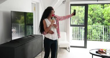 Kırmızı gül topluyor, Afro-Amerikan çift kucaklaşıyor ve sürgülü kapının yanında selfie anı yakalıyor. Romantizm, şefkat, yakınlık, yaşam tarzı, gündelik, yeşillik, ev