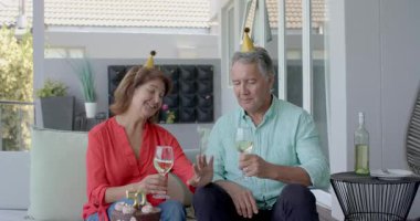 Son sınıf çifti teras kanepesinde şarap kadehi kızartıyorlar ve 50. yıl dönümü için çikolatalı pasta dilimliyorlar. Kutlama, yıldönümü, romantizm, açık hava, zarafet, arkadaşlık, kilometre taşı