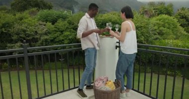 Masanın etrafında dönüp şarap dolduran, atıştırmalıkları tatmadan önce piknik battaniyesine sarılan bir çift. Eğlence, romantizm, kutlama, açık hava, eğlence, yaşam tarzı, samimiyet