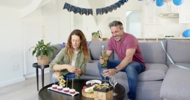 Çiftler doğum gününü evde şarap dökerek ve gülümseyerek kutluyorlar. Kutlama, romantizm, yaşam tarzı, konfor, neşe, zarafet, arkadaşlık