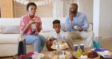 Aile evde, oturma odasında kek ve abur cuburla doğum günü kutlaması yapıyor. parti, birliktelik, mutluluk, toplanma