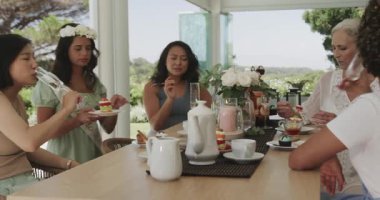 Müstakbel gelin adayı şampanya kadehi kaldırıyor, arkadaşlar verandada oturmuş pasta tadıyor. Kutlama, dostluk, açık hava, zarafet, sofistike, sağlık, brunch