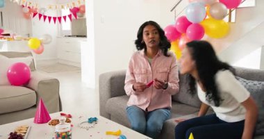 Çeşitli bayan arkadaşlar oturma odasında pasta ve peynir tepsisi tutuyorlar, balonlar var. Parti, şenlik, toplanma, sosyalleşme, ev sahipliği, atıştırma, hamur işleri