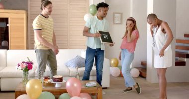 Arkadaşları evde doğum günü kutluyor, tabelayı tutuyor ve balonlarla çevrili. Kutlama, parti, mutluluk, dekorasyon, neşe, birliktelik