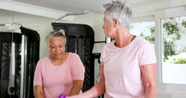 Kıdemli arkadaşlar spor salonunda fitness hedefleri peşinde koşuyorlar, egzersiz makineleri kullanıyorlar ve pozitif enerji gösteriyorlar. Fitness, determination, wellness, yoldaşlık, spor salonu, egzersiz, motivasyon, sağlık