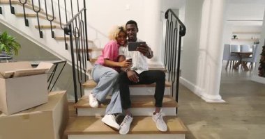 Merdivenlerde oturuyor, farklı çiftler gülümsüyor ve evde birlikte akıllı telefon izliyorlar. Teknoloji, iletişim, yaşam tarzı, bağlantı, mutluluk, açık hava