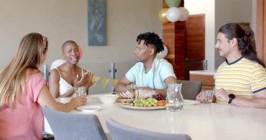 Arkadaşlar evde öğle yemeğinin tadını çıkarıyor, gülüşmeler ve sohbetler. toplanma, parti, yemek, mutluluk, bağlantı, arkadaşlık