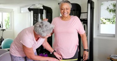 Kıdemli arkadaşlar iyi ışıklandırılmış spor salonunda, mezura ve jimnastik aletleri kullanarak sıkı antrenman yapıyorlar. Fitness, motivasyon, yoldaşlık, refah, aktif, spor salonu, güçlendirme, ilerleme