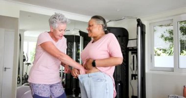 Kıdemli arkadaşlar spor salonunda çalışıyor, spor aletleriyle gelişimi kutluyorlar. Fitness, kutlama, sağlık, egzersiz, arkadaşlık, motivasyon, enerji, aktif