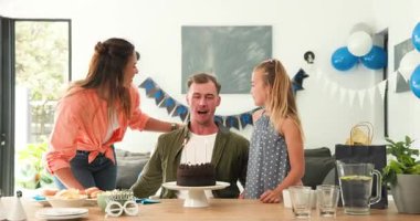 Doğum günü pastası taşıyan anne aile reisi yemek masasında şarkı söylüyor, sarılıyor ve açılış hediyesini açıyor. Aile, kutlama, neşe, birliktelik, evcil, sıcak, renkli