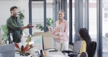 Afrikalı Amerikalı meslektaşlar ofiste toplanıyor, bilgisayar monitörünün yanındaki kutuları açıyorlar. Takım çalışması, işbirliği, üretkenlik, strateji, başlangıç, analitik, modern