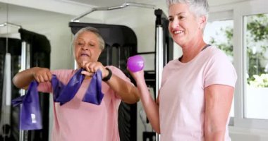 Üst düzey arkadaşlar spor salonunda mor direnç bandı ve spor aletleriyle fitness hedeflerine ulaşıyorlar. Sağlık, arkadaşlık, egzersiz, güç, fitness, motivasyon, aktif yaşam tarzı