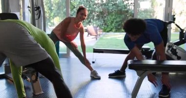 Genç bir çift ve arkadaşı spor salonunda esneyerek antrenmana hazırlanıyorlar. Fitness, egzersiz, takım çalışması, hazırlık, spor, sağlık