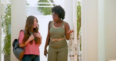 Afrika kökenli Amerikalı ve Asyalı arkadaşlar, ellerinde çantalar ve akıllı telefonlar ile güneşli koridora geliyorlar. Arkadaşlık, seyahat, çantalar, koridor, canlı, varış, macera, sıcak