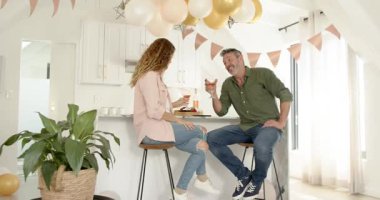 Son sınıf çifti, mutfak adasında kadeh tokuşturup kutlama yapıyor sonra da telefonları kaydırıp gülüyor. Romantizm, kutlama, yakınlık, eğlence, yaşam tarzı, modern, sıcaklık