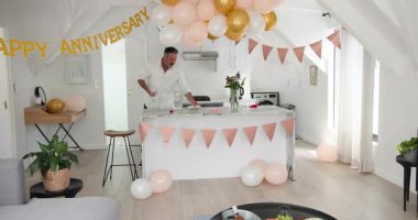 Çatı katında yıldönümü afişi, orta yaş adamı bardakları yerleştiriyor sonra da kutlamak için konfeti patlatıyor. Kutlama, parti, dekor, festival, neşe, romantizm, atmosfer