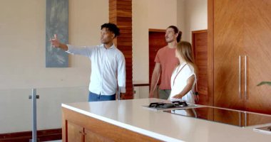 Partide, Afrikalı Amerikalı adam evdeki gülümseyen arkadaşlarına modern mutfağı gösteriyor. Misafirperverlik, dostluk, ev dekorasyonu, yaşam tarzı, etkileşim, sosyalleşme