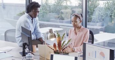 Pozitif grafik güncellemesi tespit eden siyahi meslektaşlar, masa başında takım başarısını alkışlıyorlar. İşbirliği, takım çalışması, kutlama, ofis, profesyonel başarı, çeşitlilik