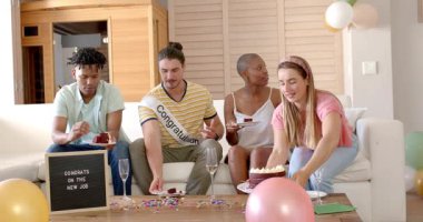 Yeni işimizi kutluyoruz, farklı arkadaşlar oturma odasında pasta ve şampanyayla eğleniyoruz. Kutlama, arkadaşlık, çeşitlilik, parti, mutluluk, yaşam tarzı