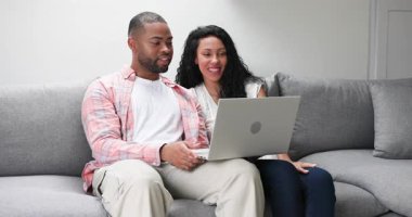 Gümüş dizüstü bilgisayarı açtıktan sonra, çeşitli çiftler oturma odasındaki kanepede sürpriz bir şekilde yazıp gülüyorlar. Romantik, samimi, samimi, teknoloji, modern, sevgi, bağlantı