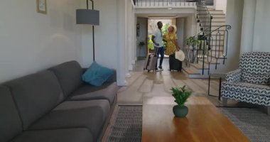 Çeşitli çiftler çantalarla modern eve giriyor, gülümsüyor ve el ele tutuşuyorlar. Seyahat, varış, taşınma, yaşam tarzı, mutluluk, ilişki