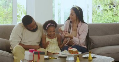 Çeşitli aileler modern oturma odasında kutlama yapıyor. Pastanın, hediye kutularının ve parti şapkalarının tadını çıkarıyorlar. Kutlama, birliktelik, mutluluk, modern, şenlikli, yaşam tarzı, bağ.