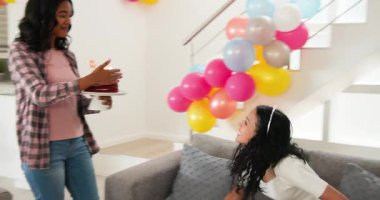 Çeşitli bayan arkadaşlar oturma odasında ellerinde kırmızı kadife pasta ve balonlarla doğum günlerini kutluyorlar. Modern, parlak, pastel, şenlikli, beklenti, gülümseme, mumlar