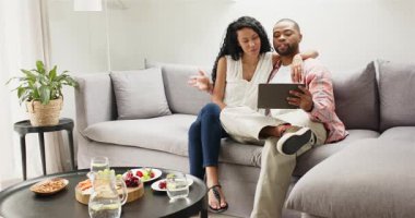 Odadaki kanepede oturan çeşitli çiftler sürahiden su döküp sohbet eden tabletleri izliyorlar. Rahatlama, samimiyet, modern yaşam tarzı, ev, bağlantı, iletişim