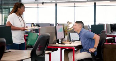 Afrika kökenli Amerikalı bir kadın doğum gününü modern ofiste pasta tutan genç bir adamla kutluyor. Kutlama, meslektaşlar, doğum günü, çalışma alanı, takım çalışması, neşe, gündelik