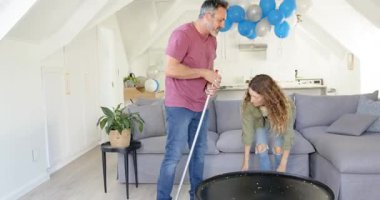 Çatı katındaki partiden sonra etrafı temizleyen, saç yolan ve kahve masasını silen bir çift. İşbirliği, yerli, düzenli, kutlama, neşeli, minimalist, neşeli