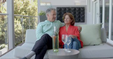 Üst düzey bir çift balkonda gülümsüyor soğuk şişeyi açıyor kadehleri kadeh kaldırma anına şarap dolduruyor. Romantik, boş zaman, zarafet, dinginlik, kutlama, açık hava, yaşam tarzı