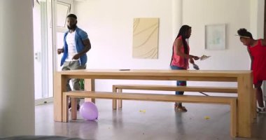 Afro-Amerikan ailesi yemek alanında parti karmaşası görüyor konfeti süpürüyor, çelenk asıyor, sarılıyor. Kutlama, şenlik, toplanma, neşe, ev dekorasyonu, samimiyet, duygusal