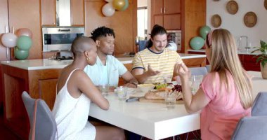 Arkadaşlar evde birlikte yemek yiyor, sofrada yemek yiyor ve gülüyorlar. Arkadaşlık, yemek, sosyalleşme, toplanma, kutlama, kaynaşma