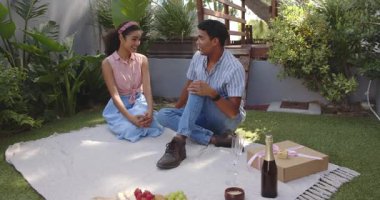 Çift yıldönümünü kutluyor ve arka bahçedeki piknikte şampanya paylaşıyor. Hediye kutusu ve meyvelerle. Kutlama, romantizm, samimiyet, piknik, bahçe, mutluluk, gurme, ortaklık