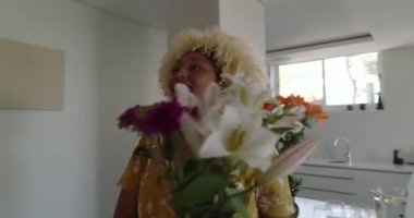 Evde doğum günü kutlaması için oturma odasında çiçek düzenleyen bir kadın. Çiçekçi, çiçek, dekorasyon, doğum günü partisi, ev dekorasyonu, düzenleme.