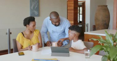Afro-Amerikan ailesi tablet ve not defteri kullanıyor, evde kaliteli zaman geçiriyorlar. teknoloji, bağlanma, eğlence, yaşam tarzı, rahatlama, yurt içi