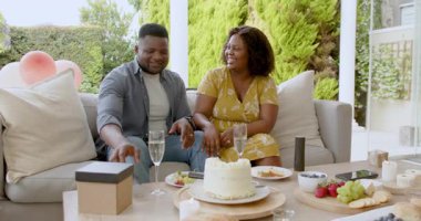 Açık havada kutlama, mutlu bir çift sıcak terasta şampanya ve pastanın tadını çıkarıyor. Kutlama, şenlik, mutluluk