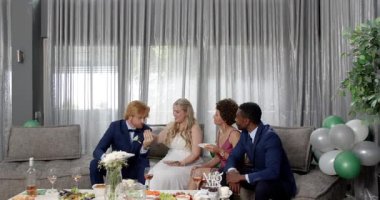 Mutlu gelin, damat ve arkadaşları oturma odasındaki düğün resepsiyonunda kadeh kaldırıyor. Kutlama, düğün, ilişki, parti ve arkadaşlık kavramı.