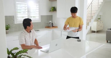 Asyalı baba ve oğul modern mutfakta evrak işlerini tartışıp sürpriz yaptılar. Aile, babalık, ebeveynlik, tartışma, iletişim, aile içi