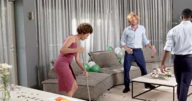 Mutlu damat ve farklı arkadaşlar oturma odasındaki düğün töreninden sonra temizlik yapıyorlar. Kutlama, düğün, ilişki, parti ve arkadaşlık kavramı.