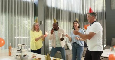 Birlikte kutlama yapan, dans eden ve ofis salonunda maytap tutan çeşitli meslektaşlarınız kutlu olsun. Kutlama, eğlence, birliktelik, ofis partisi ve iş konsepti.