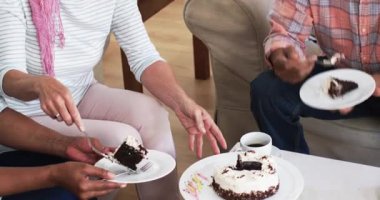 Kanepedeki çeşitli son sınıf arkadaşları ev kaldırma sunucusu, pasta dilimi kesme ve kahveyi paylaşma. Topluluk, kutlama, arkadaşlık, rahatlık, konfor, birliktelik, yakınlık