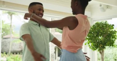 Afro-Amerikalı çift evde neşeyle dans ediyor, birbirlerine eşlik etmekten zevk alıyorlar. Dans, romantizm, mutluluk, kutlama, ilişki, eğlence