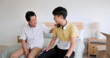 Baba ve oğul evde yatakta otururken birbirlerine hediyeler verip gülümsüyorlar. Aile, bağ, birliktelik, mutluluk, kutlama, hediyeler