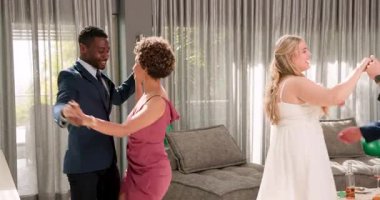 Mutlu gelin ve damat ve çeşitli arkadaşlar oturma odasında bir düğün resepsiyonunda dans ediyorlar. Kutlama, düğün, ilişki, parti ve arkadaşlık kavramı.